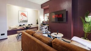 A modern living room with a sofa set, a dining area with a table and chairs, a television mounted on the wall, and a potted plant. - Bright 4BR Norton Getaway Sleeps 7 by Stay With Us (Stockton-on-Tees)