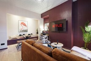 A modern living room with a sofa set, a dining area with a table and chairs, a television mounted on the wall, and a potted plant. - Bright 4BR Norton Getaway Sleeps 7 by Stay With Us (Stockton-on-Tees)