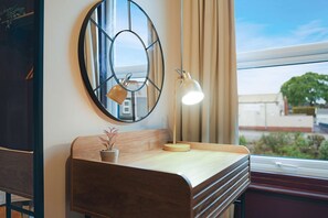 A room with a wooden bench, a round mirror, a desk with a lamp, and a view of the outside through a window. - Bright 4BR Norton Getaway Sleeps 7 by Stay With Us (Stockton-on-Tees)
