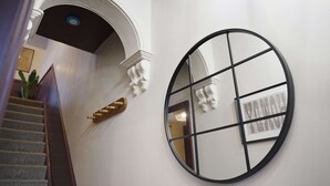 A staircase with a wooden handrail and a white wall with a circular mirror. - Bright 4BR Norton Getaway Sleeps 7 by Stay With Us (Stockton-on-Tees)
