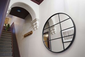 A staircase with a wooden handrail and a white wall with a circular mirror. - Bright 4BR Norton Getaway Sleeps 7 by Stay With Us (Stockton-on-Tees)