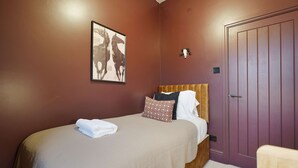 A bedroom with a bed, a headboard, a wall-mounted artwork, a door, and a towel on the bed. - Bright 4BR Norton Getaway Sleeps 7 by Stay With Us (Stockton-on-Tees)