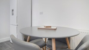 A room with a round table, two chairs, a white refrigerator, and a radiator. - Spacious Retreat With Backyard Bliss Sleeps 7 (Bishop Auckland)