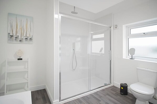 Een moderne badkamer met een douche met glazen wand, een toilet en een klein schapje met een decoratief object.