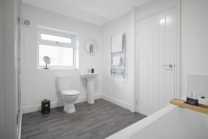 A modern bathroom with a toilet, sink, and mirror. - Spacious Retreat With Backyard Bliss Sleeps 7 (Bishop Auckland)