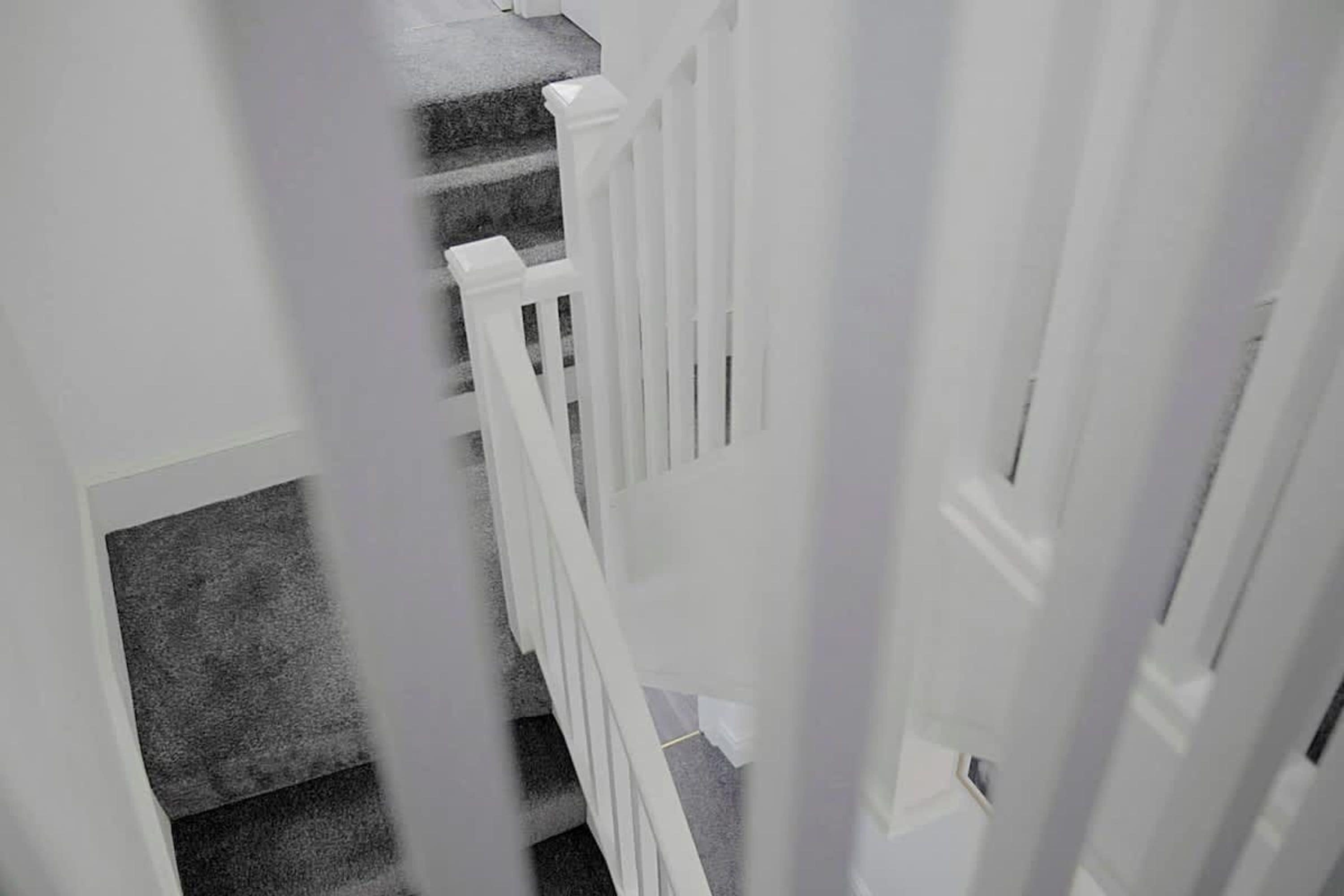 A staircase with a white railing leading to a landing.