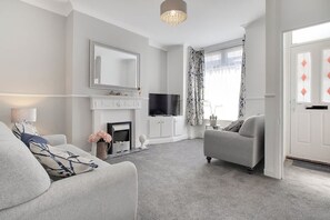 Ein modernes Wohnzimmer mit Kamin, Fernseher und Sofa.