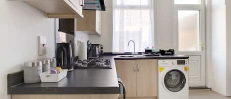 Una cocina moderna con lavadora integrada, armarios de madera y un ventanal que proporciona luz natural.