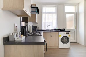 Eine moderne Küche mit Einbauwaschmaschine, Holzschränken und einem Fenster für natürliches Licht.