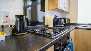 A modern kitchen with a gas stove, a kettle, and a microwave. - Central Darlington Sleeps 5 For Work or Leisure (Darlington)