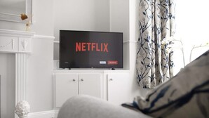 A television displaying the Netflix logo on a cabinet in a room with a white fireplace and curtains. - Central Darlington Sleeps 5 For Work or Leisure (Darlington)