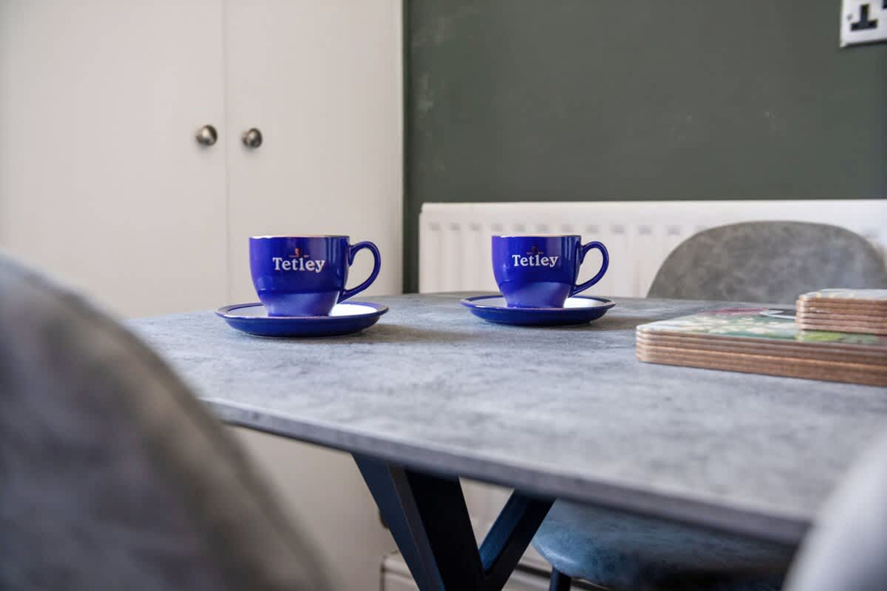 A table with two blue cups and saucers, a stack of books, and a white radiator.