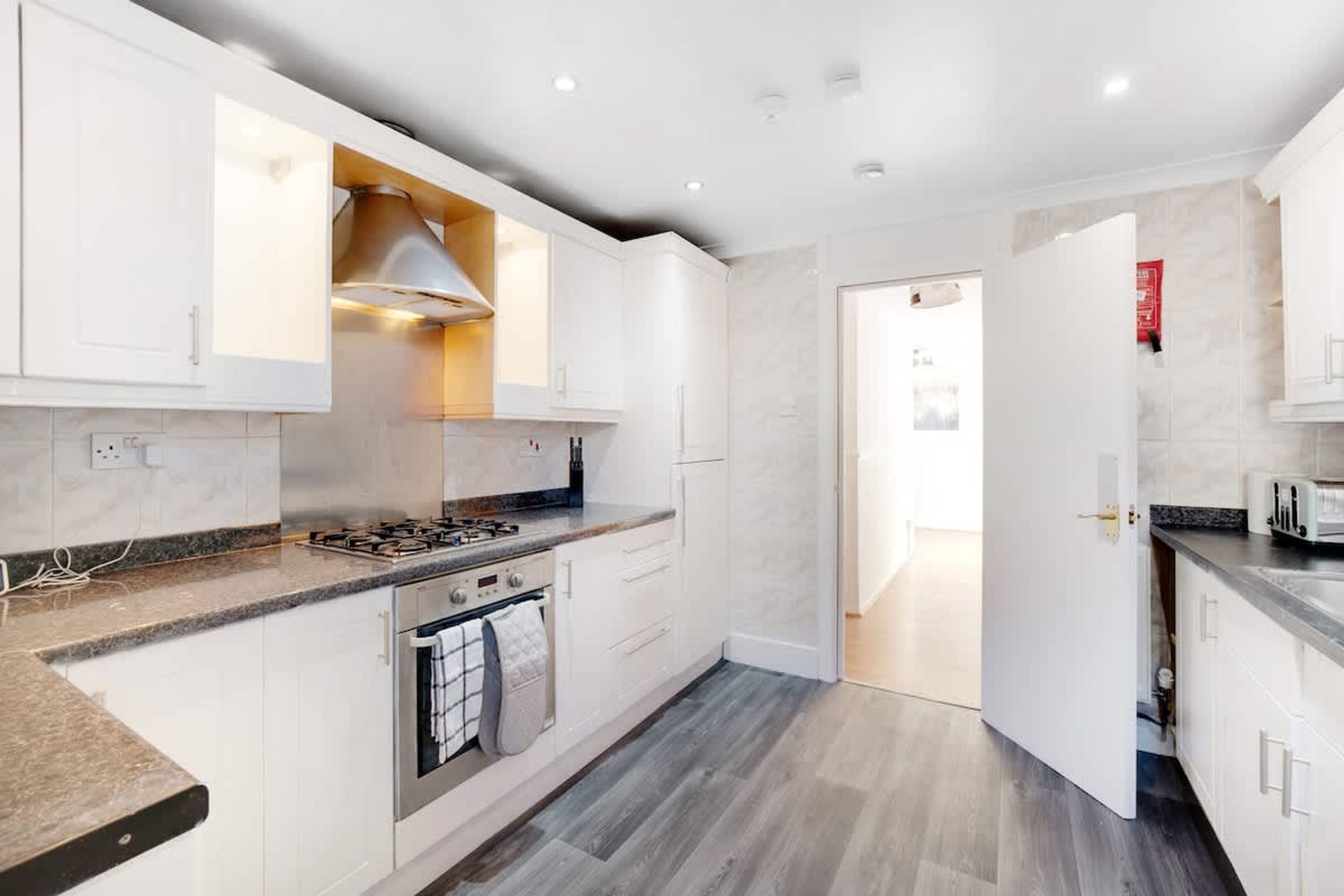 A modern kitchen with white cabinetry, a gas stove, and a built-in oven.