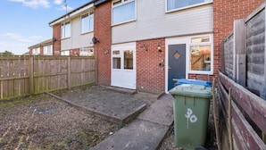A residential area with two brick houses, a wooden fence, and a green bin. - 4BR in Stafford Place Sleeps 7 Wifi Free Parking (Peterlee)