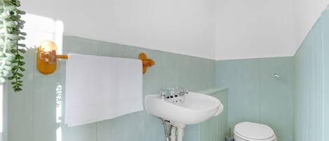 Une salle de bain avec un lavabo blanc, des toilettes et un porte-serviettes.