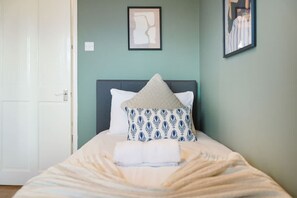 A bedroom with a bed, pillows, and a framed picture on the wall. - Charming 3 Bedroom Home Near Coast Town (Redcar)