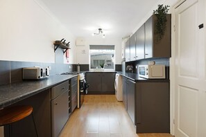 A modern kitchen with a toaster, microwave, and a sink. - Charming 3 Bedroom Home Near Coast Town (Redcar)
