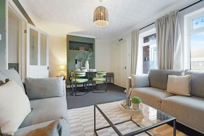 Ein modernes Wohnzimmer mit einer Sofagarnitur, einem Glastisch und einem Essbereich mit Stühlen und einem Tisch.
