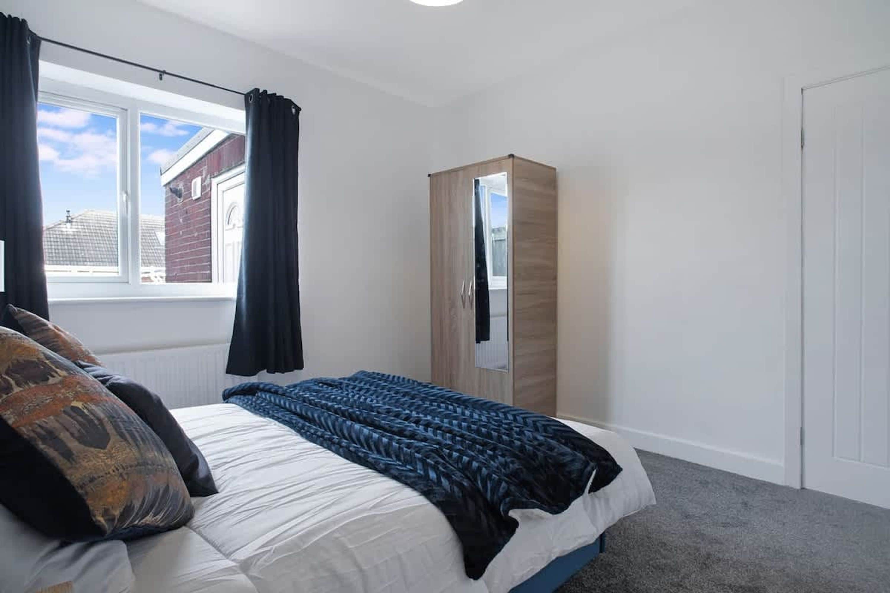A bedroom with a bed, a wardrobe, a window, and a view of the outside.