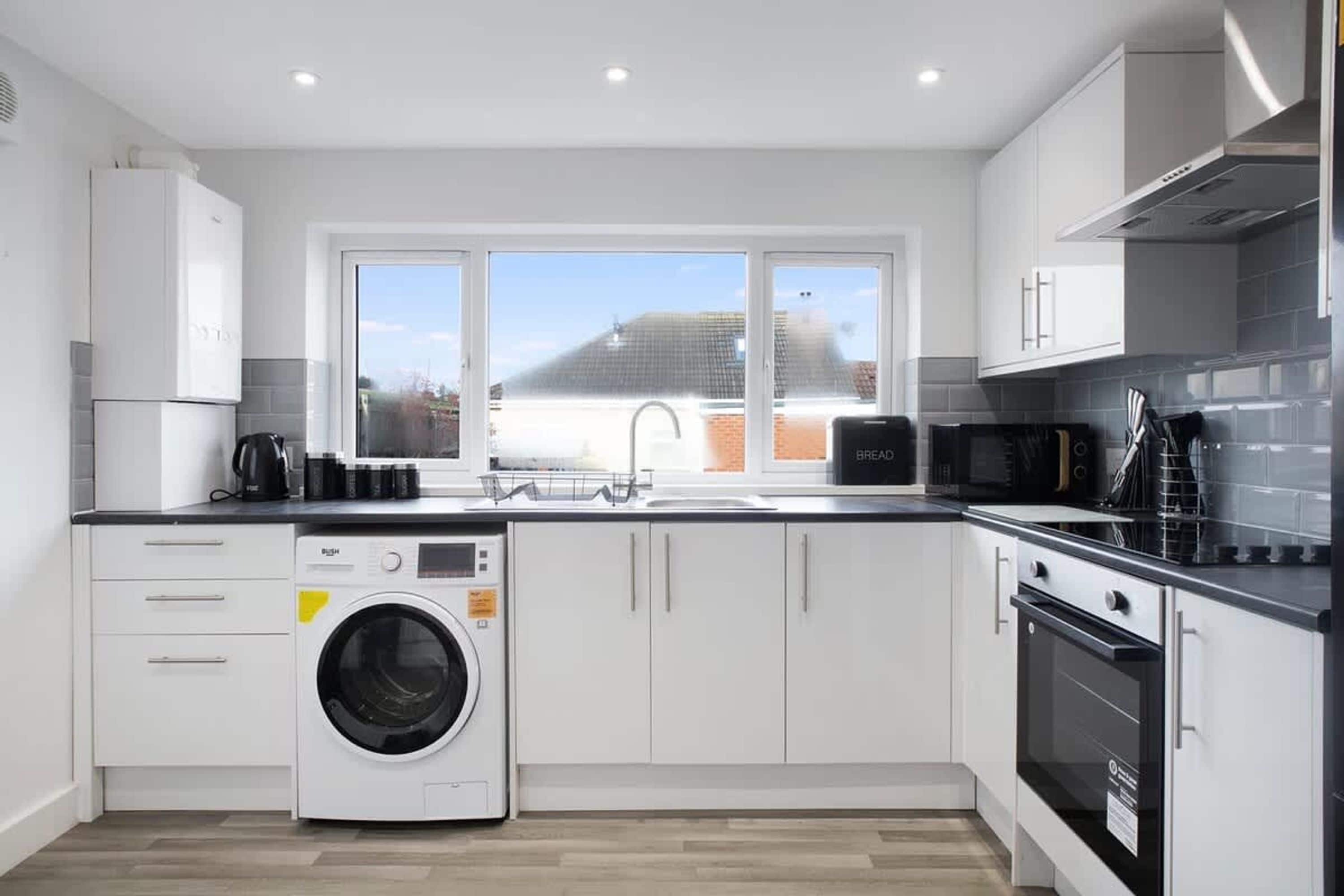 Une cuisine moderne équipée d’un lave-linge, d’un four à micro-ondes et d’une cuisinière.