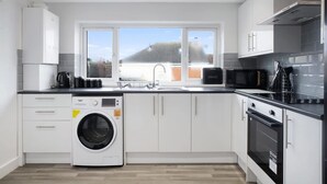 Une cuisine moderne équipée d’un lave-linge, d’un four à micro-ondes et d’une cuisinière.