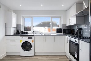 A modern kitchen with a built-in washing machine, a microwave, and a stove. - Spacious Living Room and Modern Comforts Sleeps 4 (Peterlee)