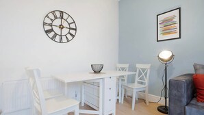 A modern living room with a white dining table, chairs, a floor lamp, and a wall clock. - Sunderland 3BR Retreat Sleeps 6 by Stay With Us (Sunderland)