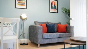 A living room with a grey sofa, a round coffee table, a floor lamp, and a white chair. - Sunderland 3BR Retreat Sleeps 6 by Stay With Us (Sunderland)