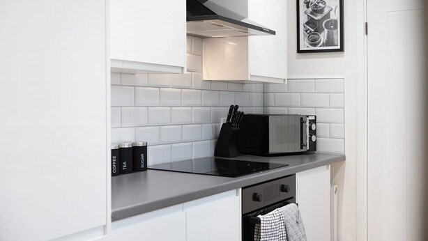 A kitchen with white cabinets, a microwave, and a stove. - Sunderland 3BR Retreat Sleeps 6 by Stay With Us (Sunderland)