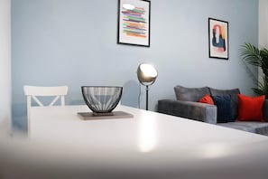 A modern living room with a white dining table, a black and white bowl centerpiece, a floor lamp, and a grey sofa with red and blue cushions. - Sunderland 3BR Retreat Sleeps 6 by Stay With Us (Sunderland)