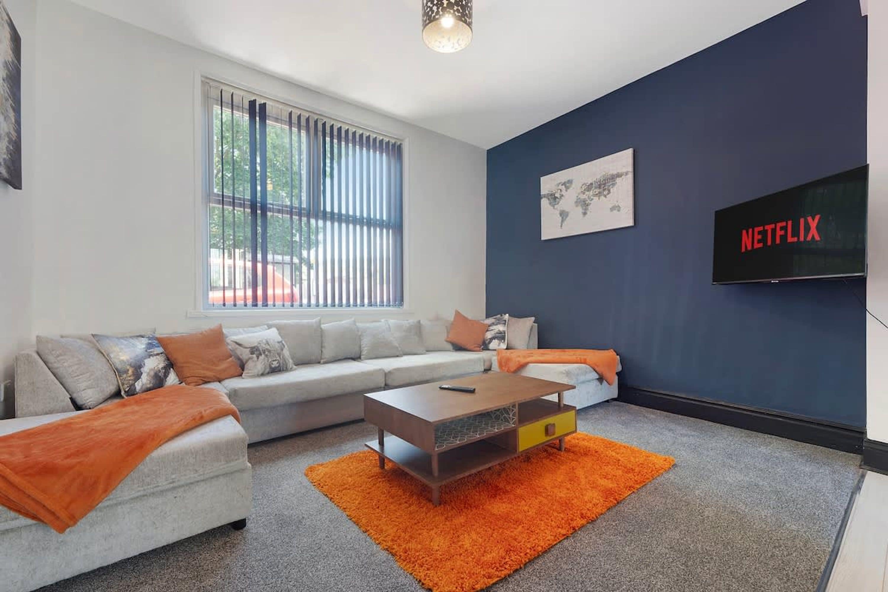 Ein modernes Wohnzimmer mit Sofa, Couchtisch und einem Fernseher, der 'NETFLIX' anzeigt.