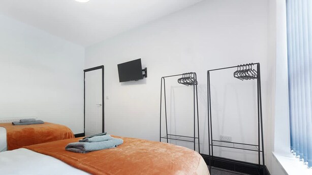 A hotel room with two beds, a flat-screen TV, and a wardrobe with a mirror. - 5BR Sleeps 10 Perfect for Contractors in Durham (Durham)