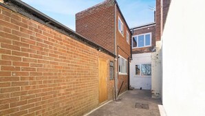A narrow alleyway with a brick wall on one side and a building with a window on the other. - 5BR Sleeps 10 Perfect for Contractors in Durham (Durham)