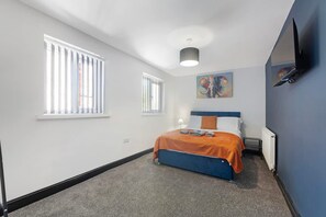 A bedroom with a bed, two windows, a painting, and a radiator. - 5BR Sleeps 10 Perfect for Contractors in Durham (Durham)