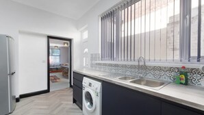 A modern kitchen with a washing machine, a sink, and a window with blinds. - 5BR Sleeps 10 Perfect for Contractors in Durham (Durham)