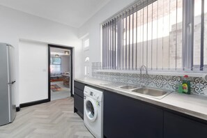 A modern kitchen with a washing machine, a sink, and a window with blinds. - 5BR Sleeps 10 Perfect for Contractors in Durham (Durham)
