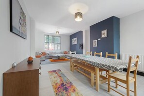 A dining area with a long table, chairs, and a bench. There is a sofa and a window with blinds in the background. - 5BR Sleeps 10 Perfect for Contractors in Durham (Durham)