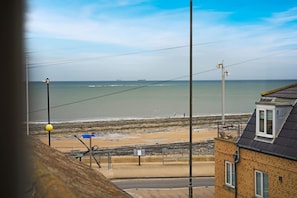 Blick auf die Küste mit Strand, einer Straße und einem Gebäude mit geneigtem Dach.