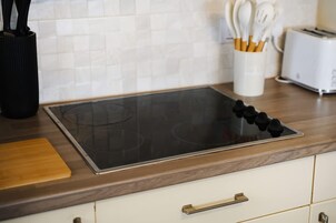 Una cocina con una placa de inducción negra, un tostador y un portalapices en la encimera.