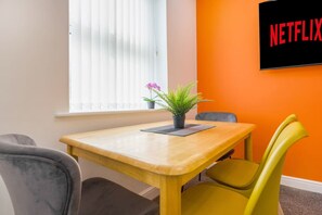 A room with a wooden table, two chairs, a potted plant, and a wall-mounted sign. - Stylish 5 Bed Flat in Thornaby Ideal for Groups (Stockton-on-Tees)