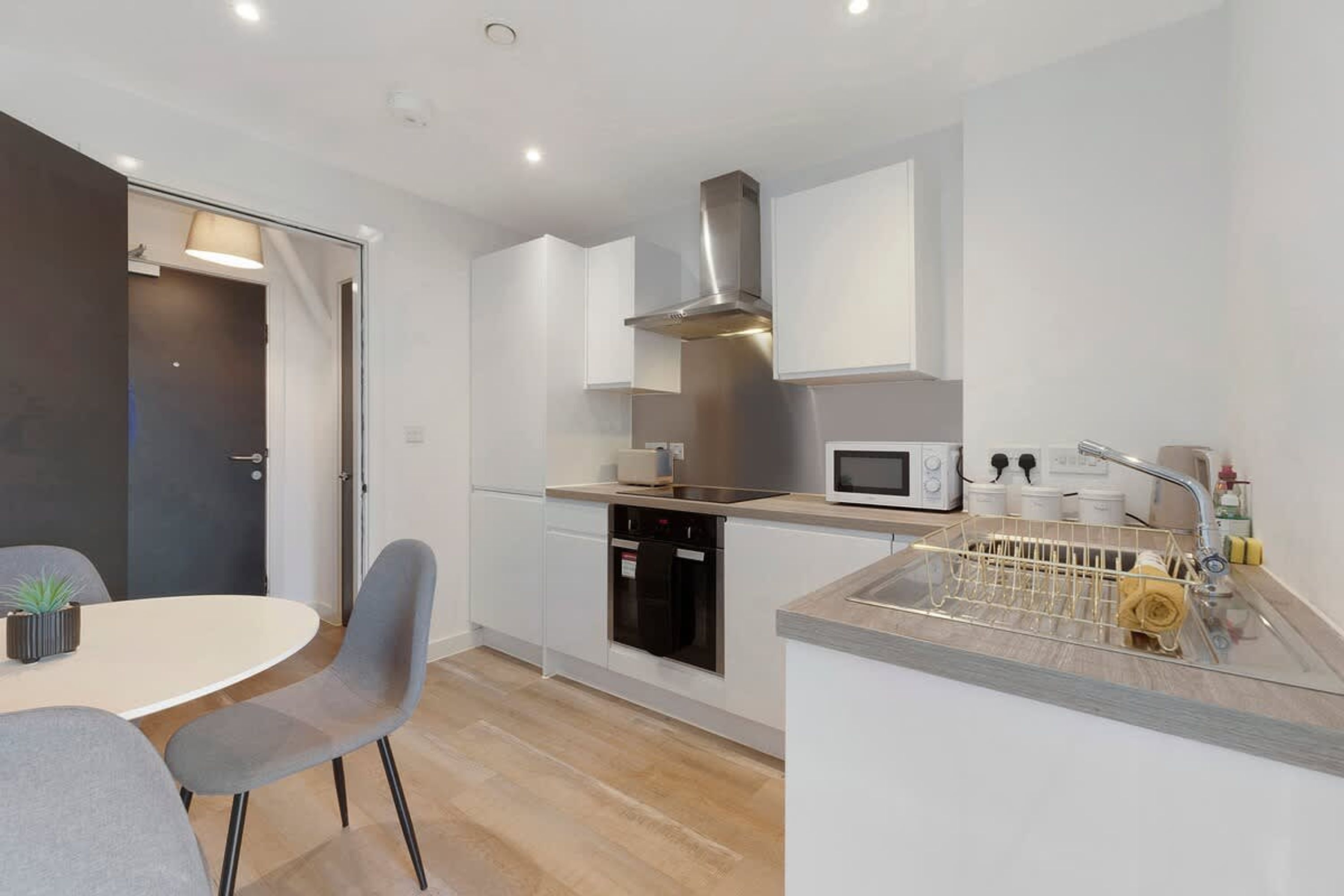 A modern kitchen with a microwave, stove, and dishwasher. There is a dining area with a table and chairs.
