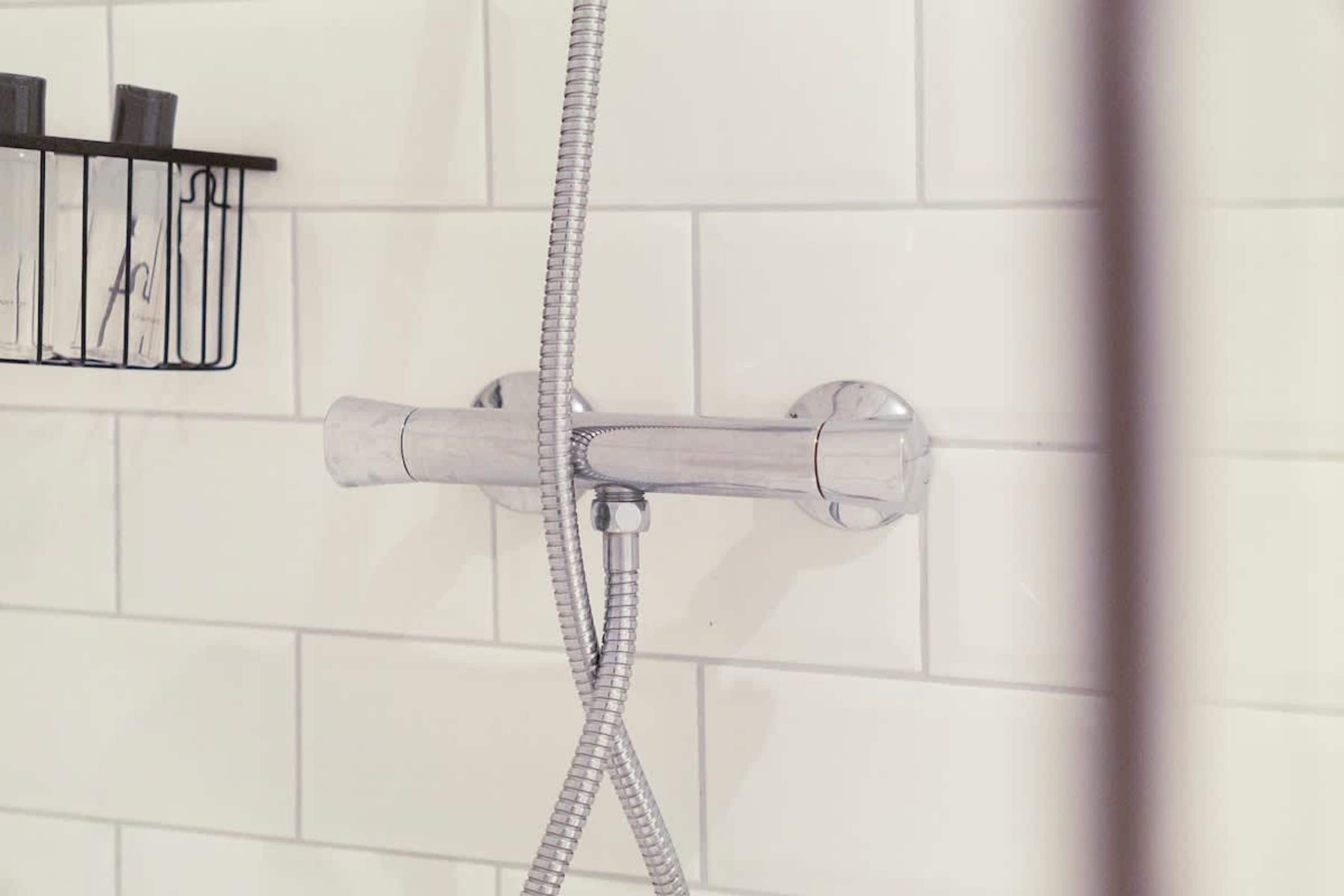 Ducha con manguera flexible y grifo de pared.
