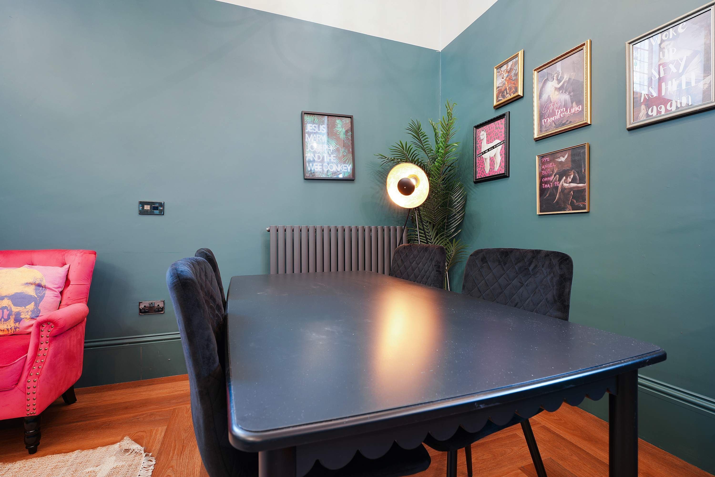 Un comedor con una mesa y sillas, un radiador y obras de arte enmarcadas en la pared.