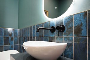 A bathroom with a white sink, a black faucet, and blue-tiled walls.