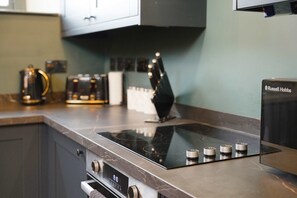 Una cocina con estufa integrada, horno y cafetera en la encimera.