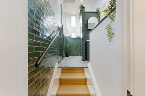 A staircase with a metal handrail, a tiled wall, and a plant on the right. - Central Hartlepool 2BR Retreat Sleeps 3 by Stay With Us (Hartlepool)