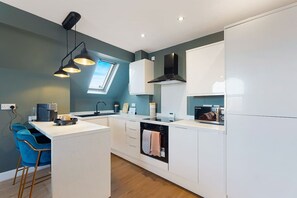 Eine moderne Küche mit weißen Schränken, einer zentralen Kochinsel, einem eingebauten Backofen und einem Fenster über der Spüle.