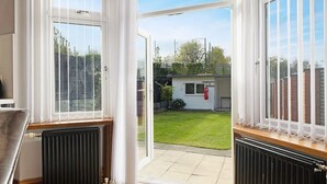 A room with a view of a backyard, a radiator, and a window with white curtains. - 3BR in Baxter Avenue With Netflix Wifi Backyard (Newcastle-upon-Tyne)
