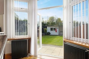 A room with a view of a backyard, a radiator, and a window with white curtains. - 3BR in Baxter Avenue With Netflix Wifi Backyard (Newcastle-upon-Tyne)