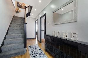 A staircase leading to a landing with a 'HOME' sign, a mirror, and a patterned rug. - 3BR in Baxter Avenue With Netflix Wifi Backyard (Newcastle-upon-Tyne)